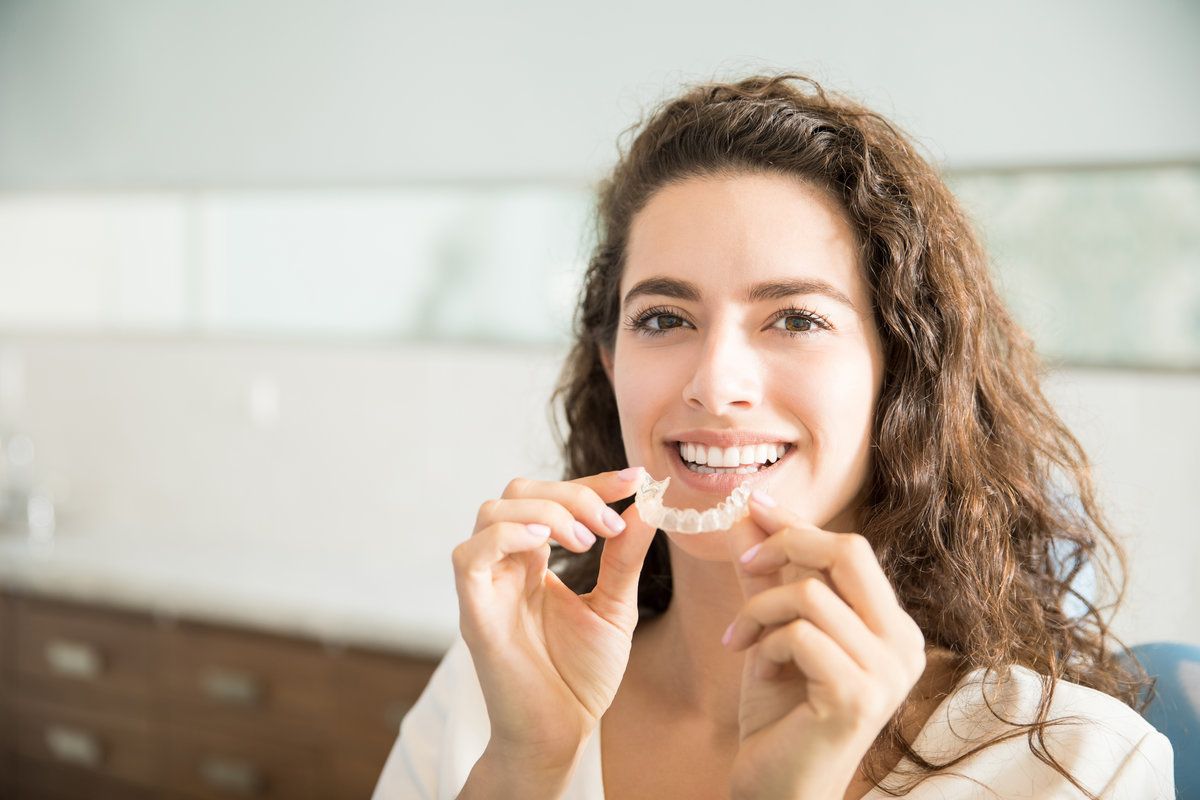 Beautiful Patient Holding Clear Orthodontic Aligner In Dental Clinic