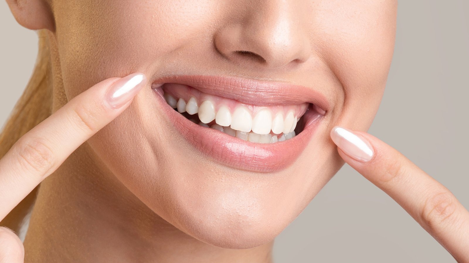 image-1790625550306 Woman pointing to her bright, whitened smile after a holistic teeth whitening treatment at Rose Dental